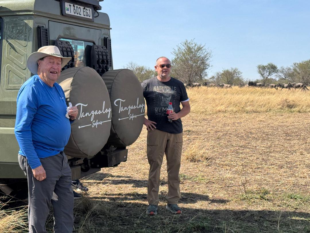Tanzaology guides with guests beside a safari vehicle